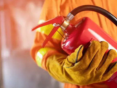 man holding fire extinguisher with orange gloves 